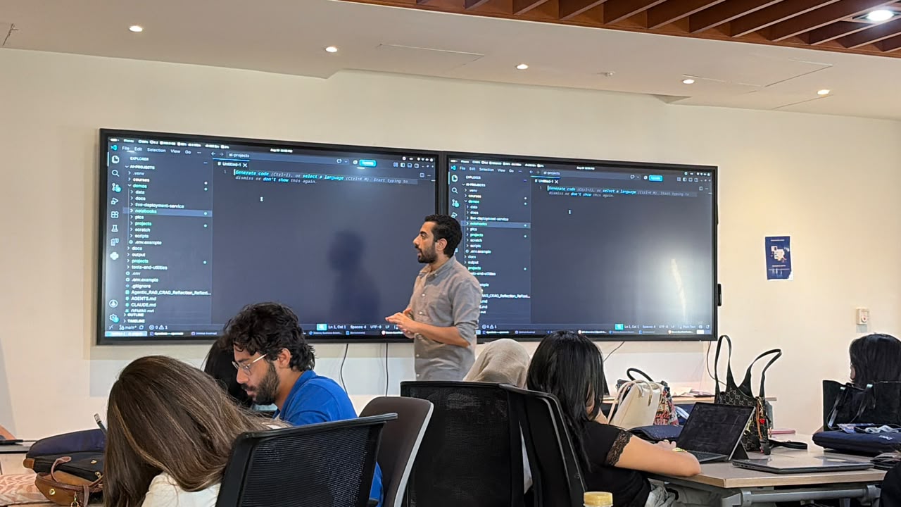 Standing between two large screens while walking trainees through code