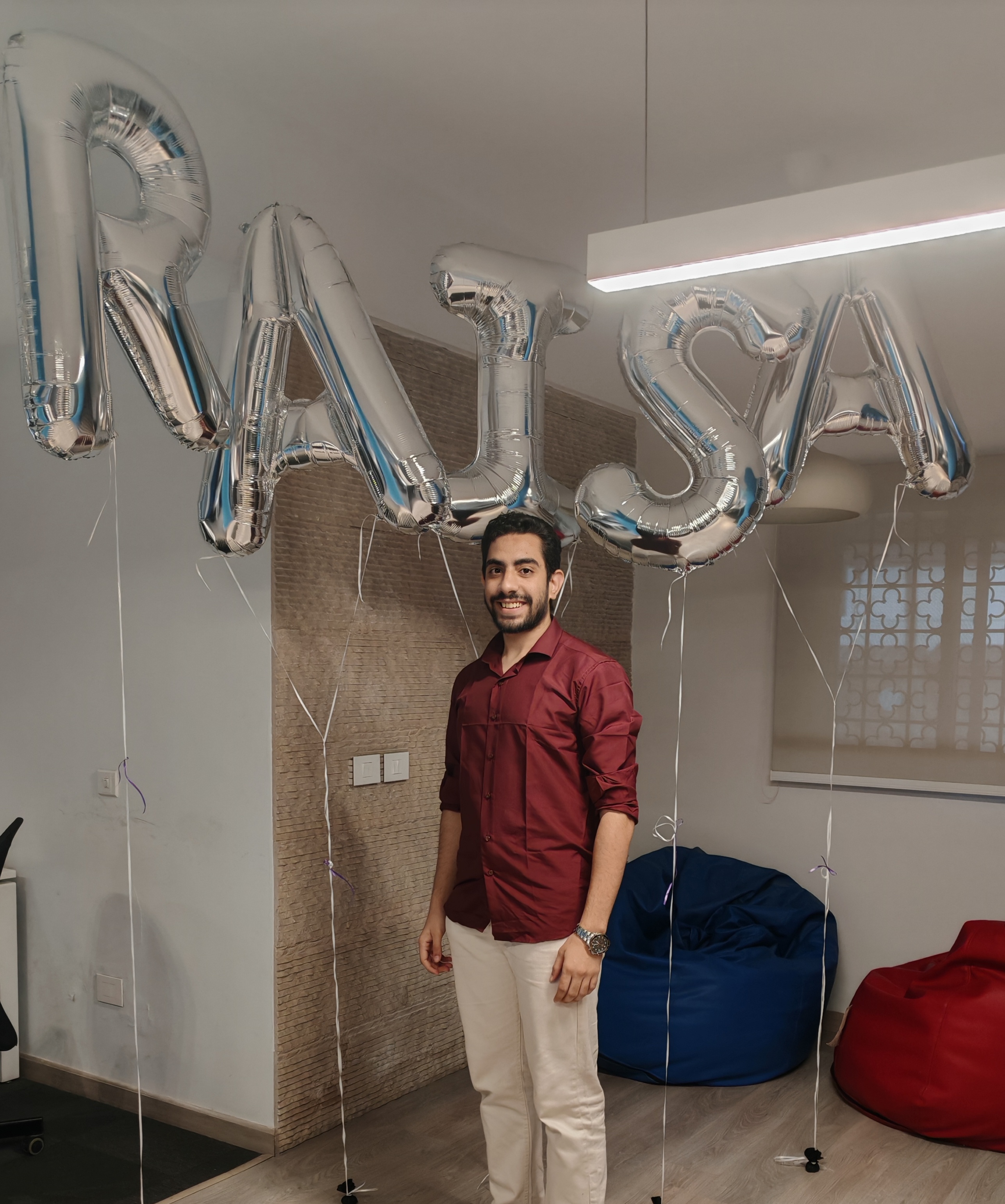 Standing under RAISA balloon letters at a team celebration